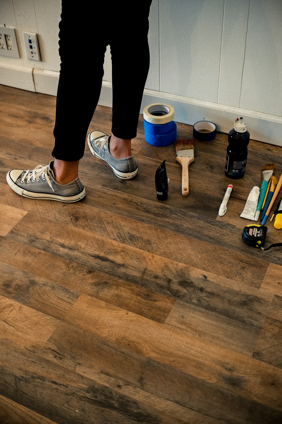 person-in-black-pants-and-white-and-black-nike-sneakers-standing-on-brown-wooden-floor-efcrlqm9ki4