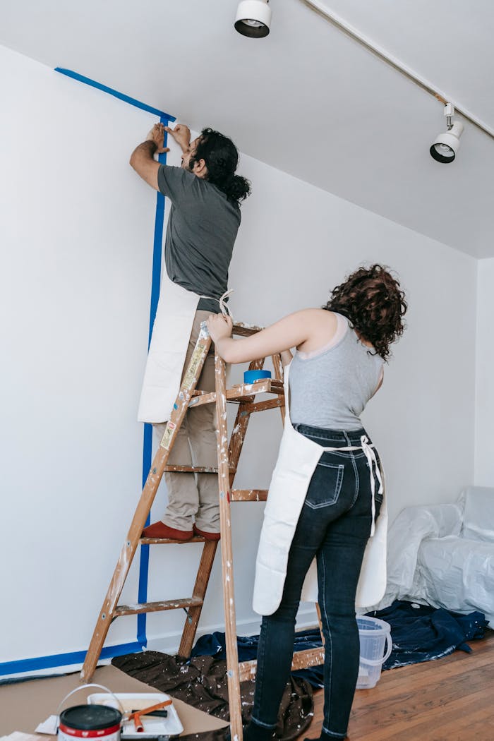 Couple working together on home renovation, painting walls in new apartment.